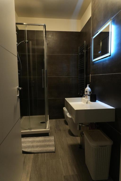 Bagno con doccia in vetro, lavabo e specchio illuminato
